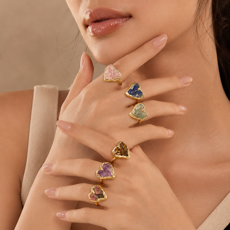 Lifestyle product image showing multiple natural crystal heart rings worn on hands with a soft beauty portrait background.